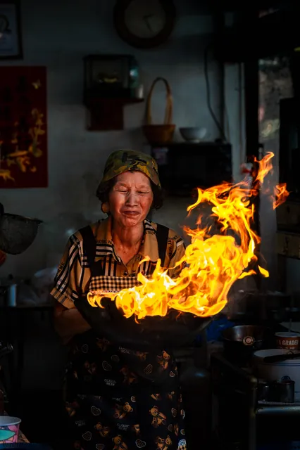 Street cook with a flaming wok